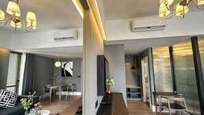 Una habitación de hotel moderna con sofá, una mesa de comedor, una mesita de centro y televisor.