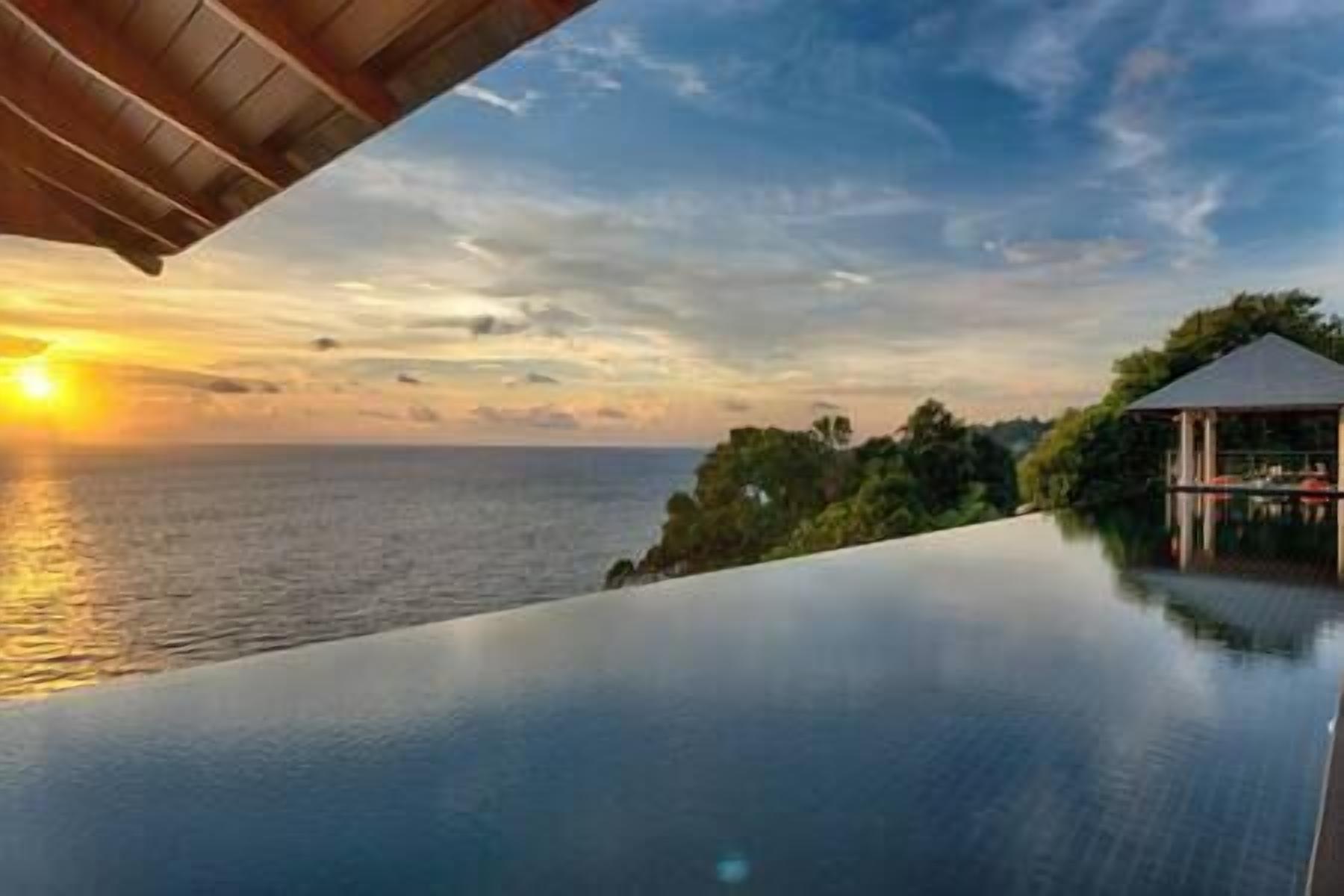 A serene infinity pool overlooking the ocean at sunset.
