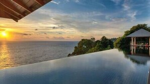 A serene infinity pool overlooking the ocean at sunset.