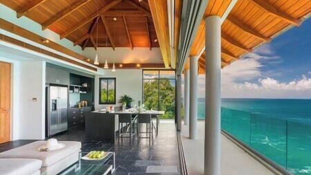 A modern interior with a kitchen, dining area, and a balcony with a view of the ocean.