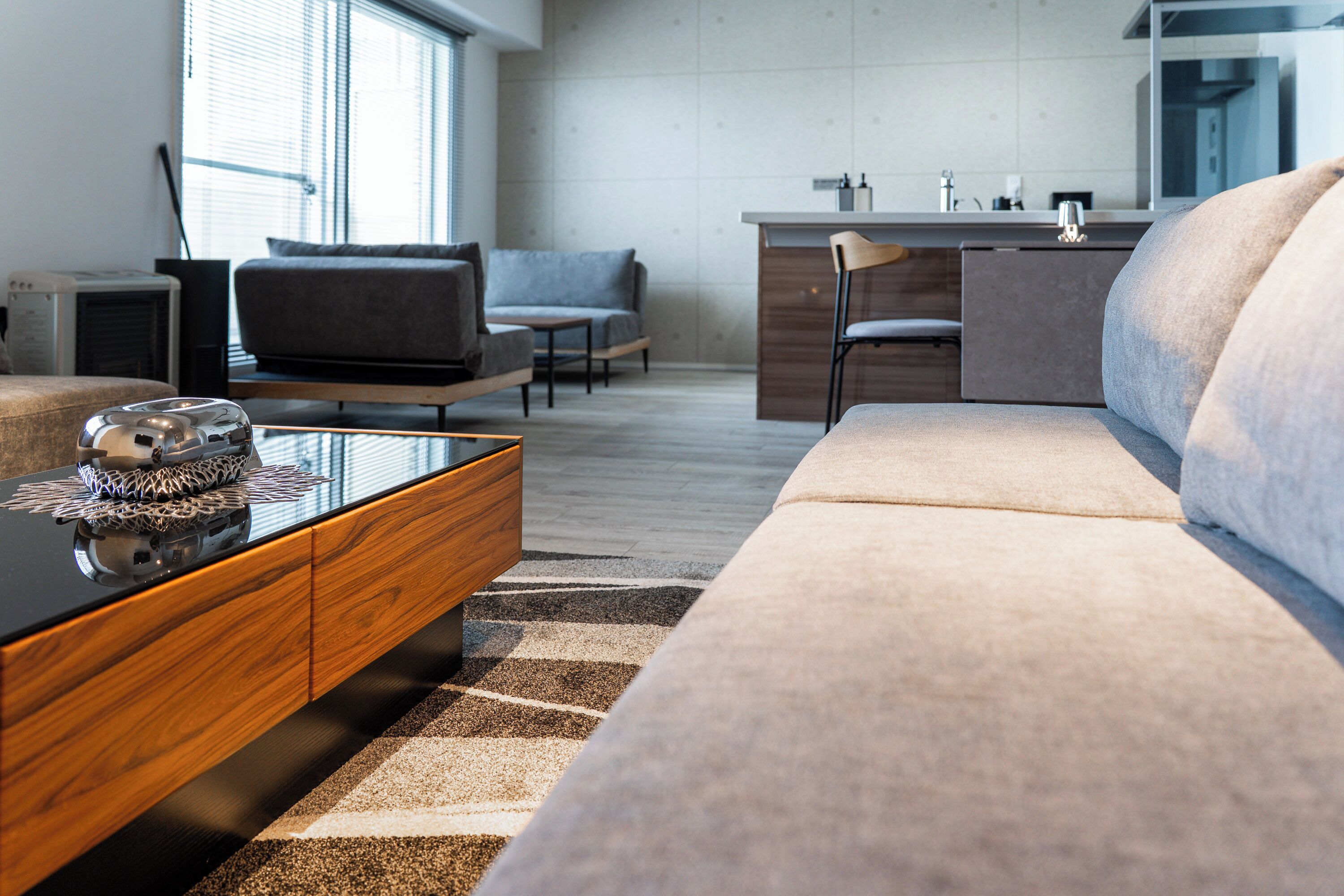 A modern living room with a sofa, coffee table, and a kitchen area in the background.