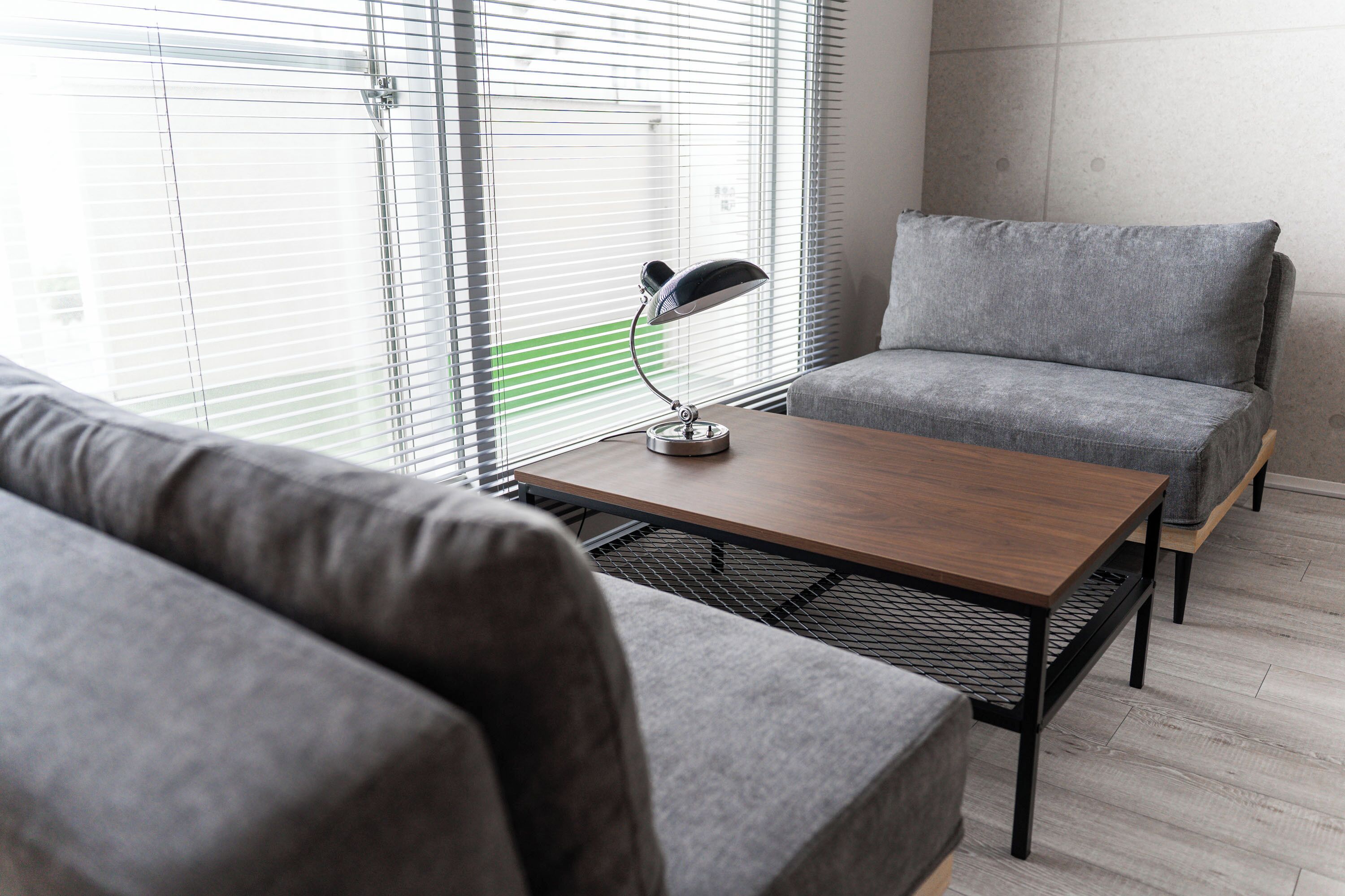 Un salon moderne avec un canapé gris, une table basse en bois et un lampadaire.