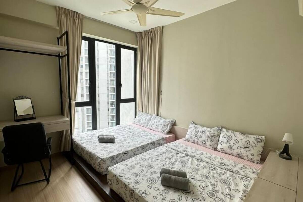 A bedroom with two beds, a desk, a chair, a ceiling fan, and a window with curtains.