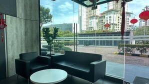 A modern interior with a glass wall, black leather seating, and a round table. - JazzA Suite by Homey Planet (Tanjung Tokong)