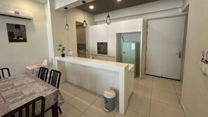 A modern kitchen with a central island, a dining area with a table and chairs, and a closed door. - JazzA Suite by Homey Planet (Tanjung Tokong)