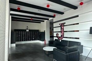 A modern lobby with black and white decor, a reception desk, and seating area. - JazzA Suite by Homey Planet (Tanjung Tokong)