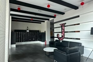 A modern lobby with black and white decor, a reception desk, and a large decorative letter 'J'. - JazzA Suite by Homey Planet (Tanjung Tokong)