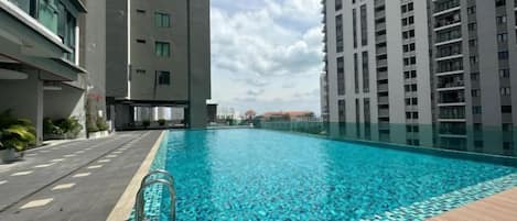 A swimming pool surrounded by high-rise buildings, with a clear sky above.