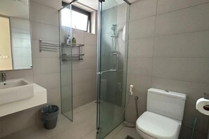 A bathroom with a glass-enclosed shower, a toilet, a sink, and a mirror. - JazzA Suite by Homey Planet (Tanjung Tokong)