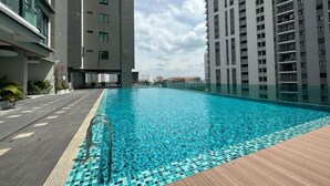 A swimming pool with a tiled deck, surrounded by high-rise buildings. - JazzA Suite by Homey Planet (Tanjung Tokong)