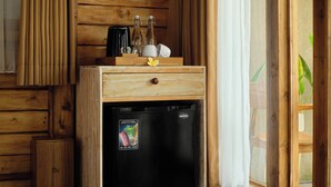 Een compacte kitchenette met een koelkast, een klein kastje en een houten ladeunit.