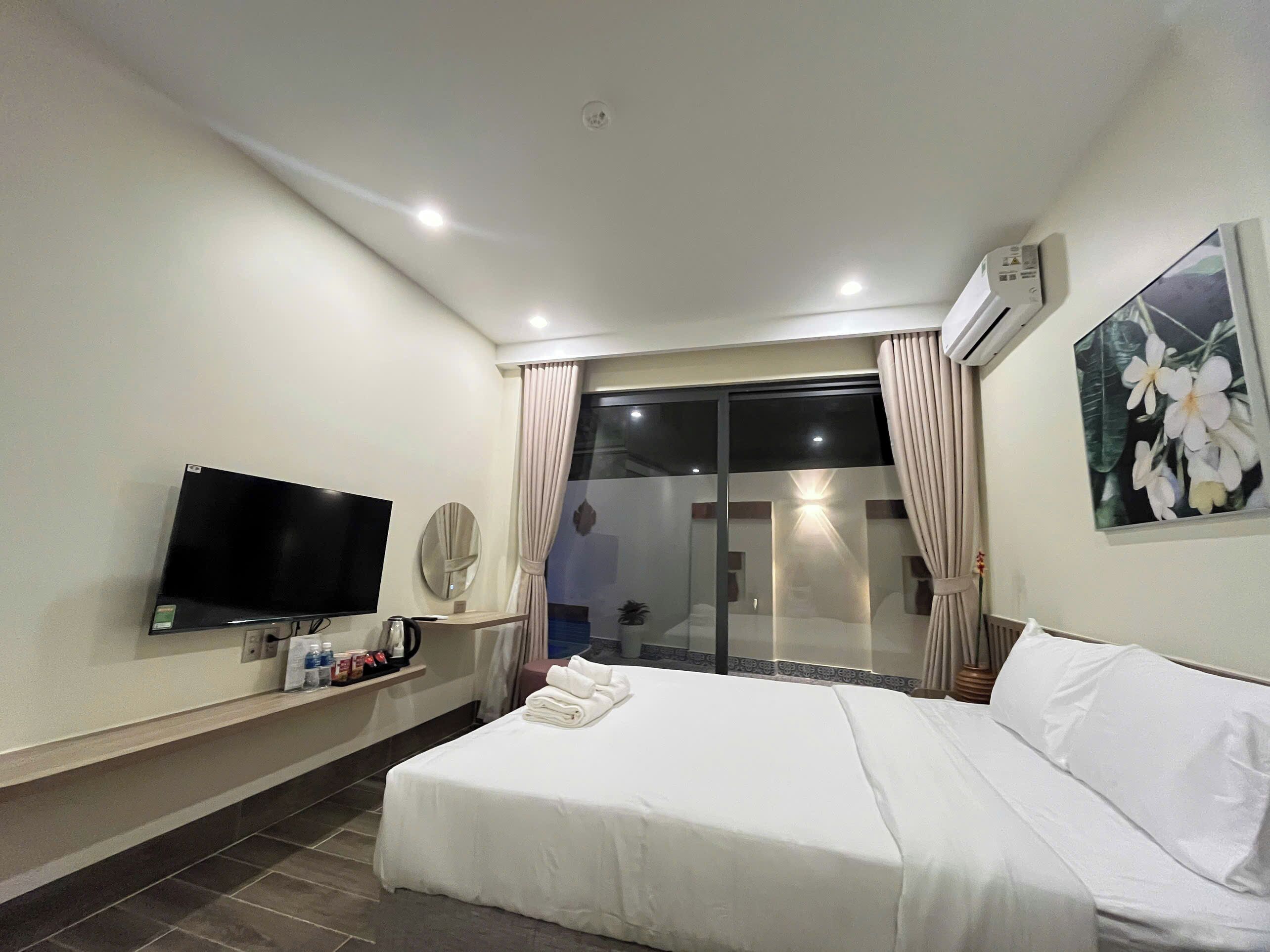 A hotel room with a bed, a TV, a coffee maker, and a window with curtains.