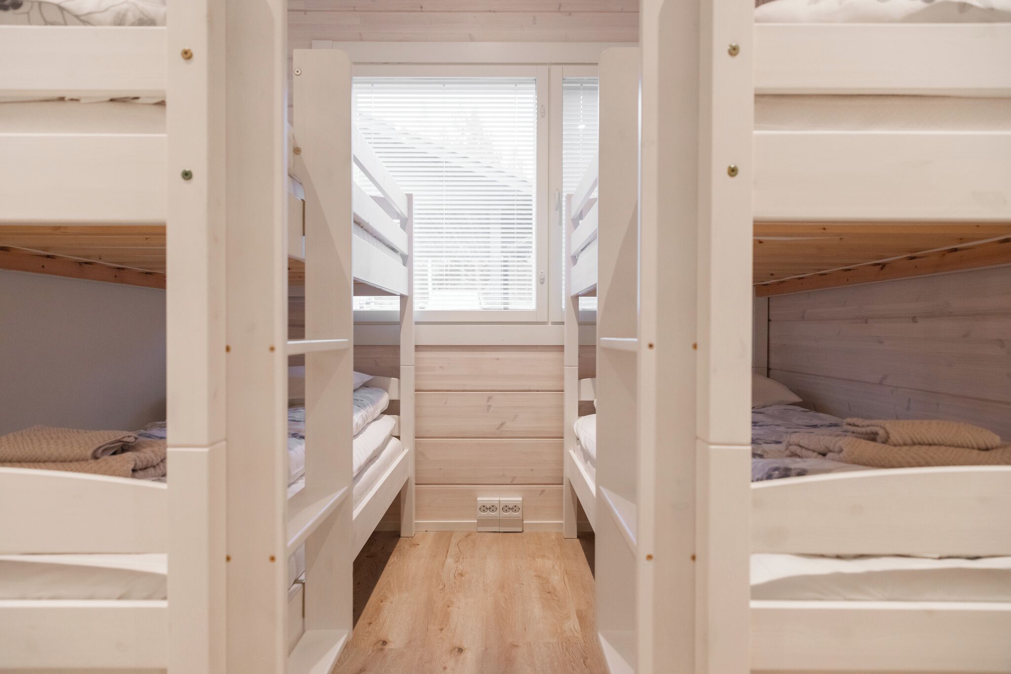 A dormitory room with bunk beds, a skylight, and a wooden floor.