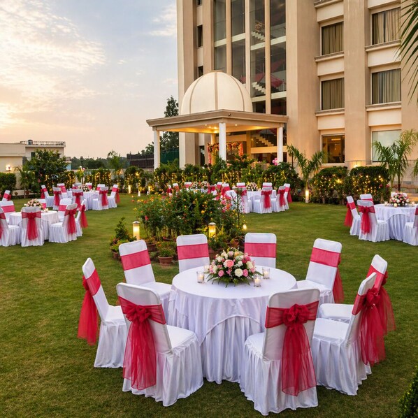 A formal outdoor event setup with round tables and chairs, surrounded by greenery and a building in the background. - 8fold by LaRiSa, Basti (Basti)