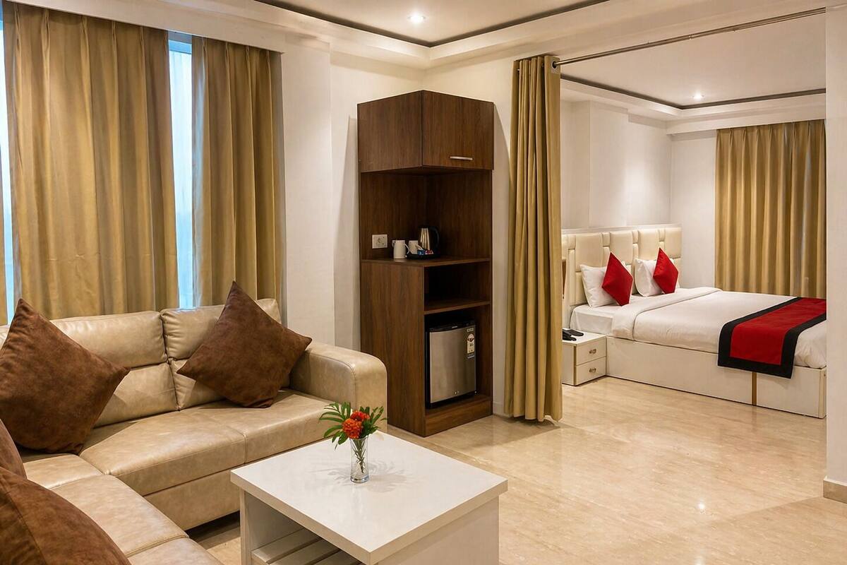 Habitación de hotel con sofá, una mesa de centro con un jarrón, cama con almohadas rojas, mesita de noche y armario.