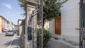 A street view with a building featuring a wooden door and a metal gate.
