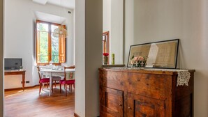 A room with a wooden cabinet, a dining table with chairs, and a television.