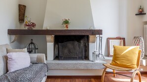 A living room with a fireplace, a sofa, a chair, and a small table with decorative items.