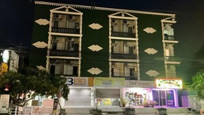 Un immeuble à plusieurs étages doté de balcons, une devanture de magasin avec une enseigne au néon et une affiche pour « BB Broadband ».