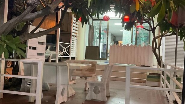 Un espace aménagé avec des tables et des chaises, une clôture en bois et un panneau indiquant « Appartement à louer ».
