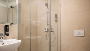 Ein modernes Badezimmer mit Duschkabine aus Glas, einem weißen Waschbecken und einer Toilette.