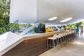 Un área de bar al aire libre con mostrador, taburetes y un letrero.