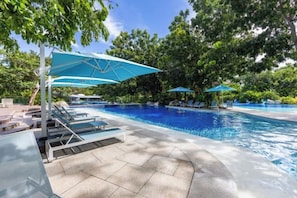 Un área de piscina con sillones de playa y sombrillas.