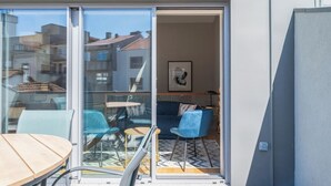 A modern apartment with a sliding glass door leading to a balcony with a table and chairs.