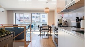 A modern kitchen with a dining area, large windows, and a view of the city.