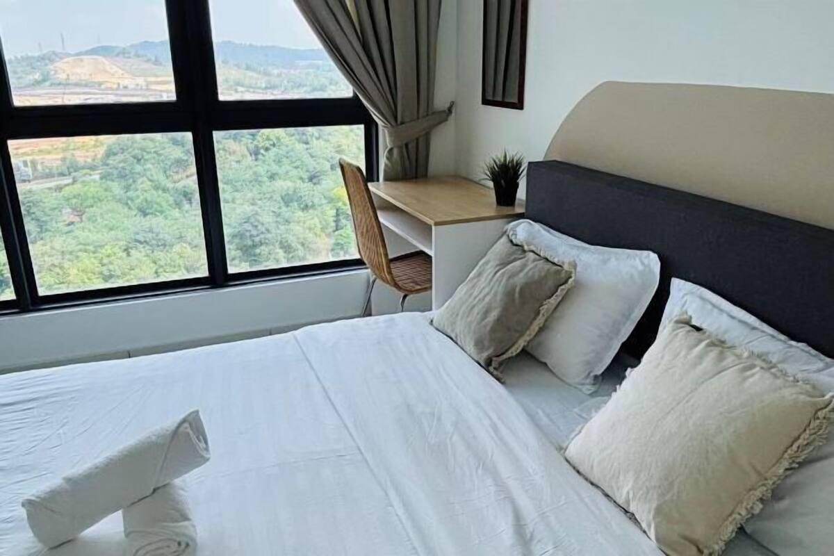Ein Hotelzimmer mit Bett, Schreibtisch und Stuhl. Ein Fenster bietet Blick auf Grünflächen und Hügel.