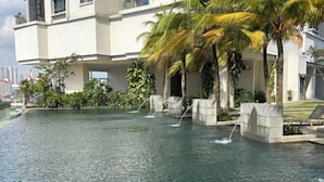 Un edificio moderno con piscina, palmeras y cielo despejado.
