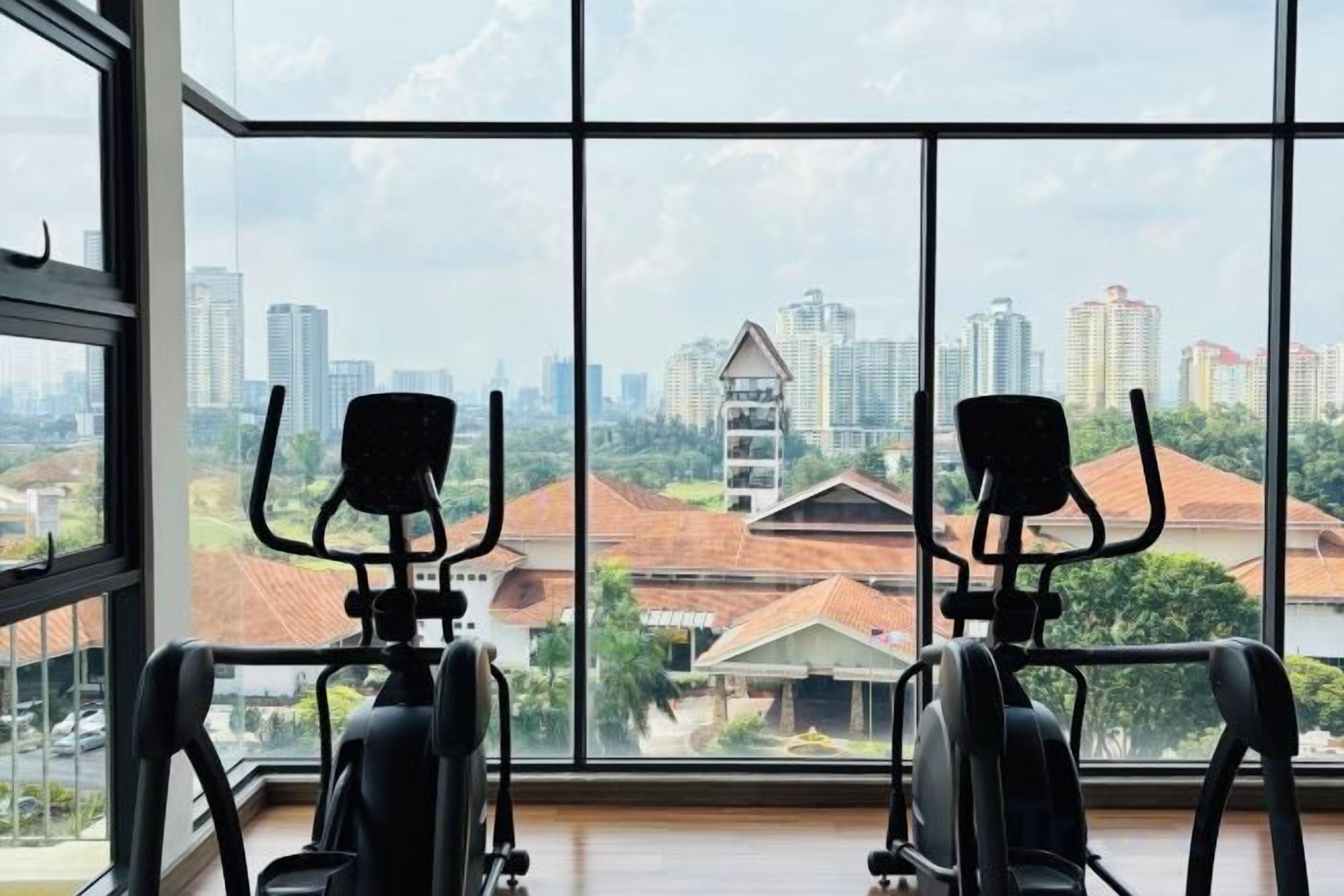 A gym with exercise equipment and a large window offering a city view.