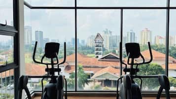 A gym with exercise equipment and a large window offering a city view.
