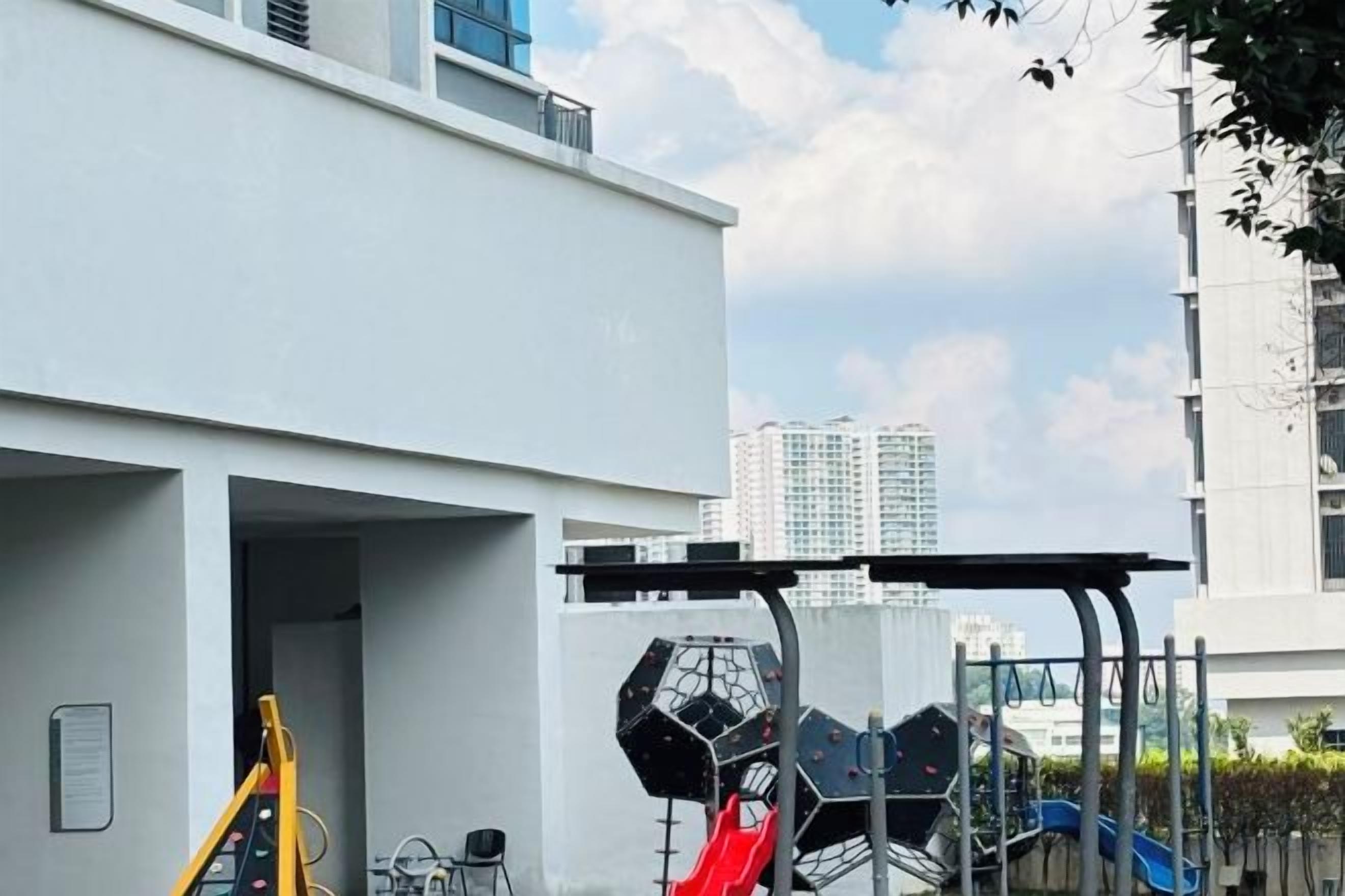 A playground with slides and a climbing structure, adjacent to a building with a balcony.