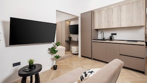 A modern kitchen with wooden cabinets, a black countertop, and a built-in oven. There is a small black table with a plant and a remote control. - Marvie Apartments (Rijeka)
