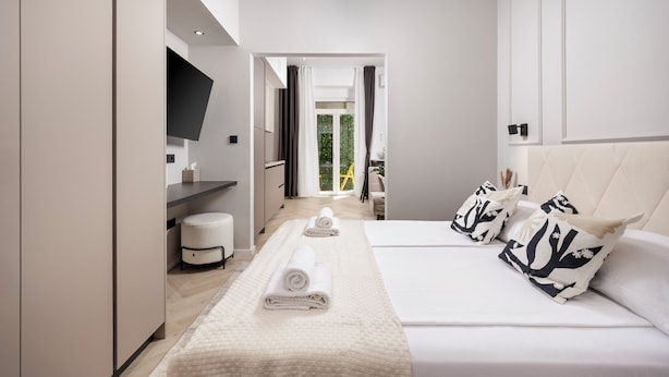 A modern hotel room with a large bed, a flat-screen TV, a bedside table, and a view of the outdoors. - Marvie Apartments (Rijeka)