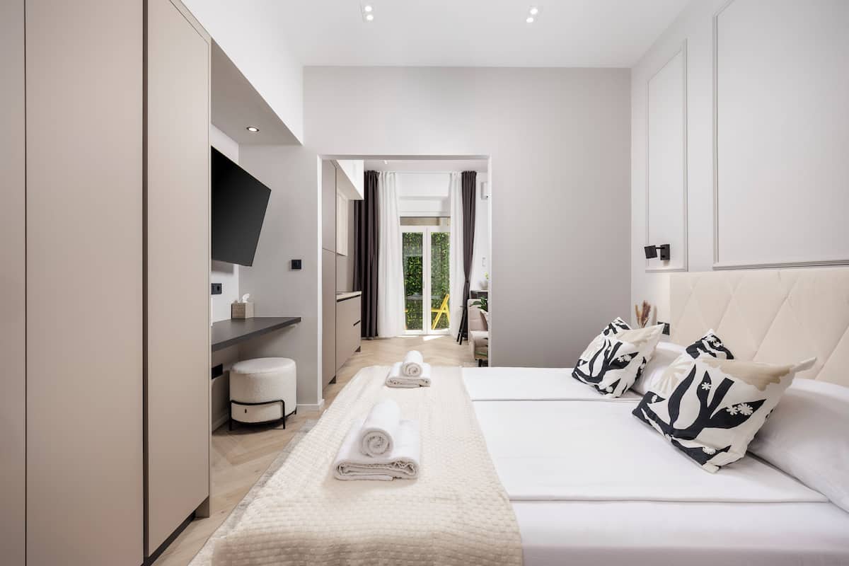A modern hotel room with a large bed, a flat-screen TV, a bedside table, and a view of the outdoors.