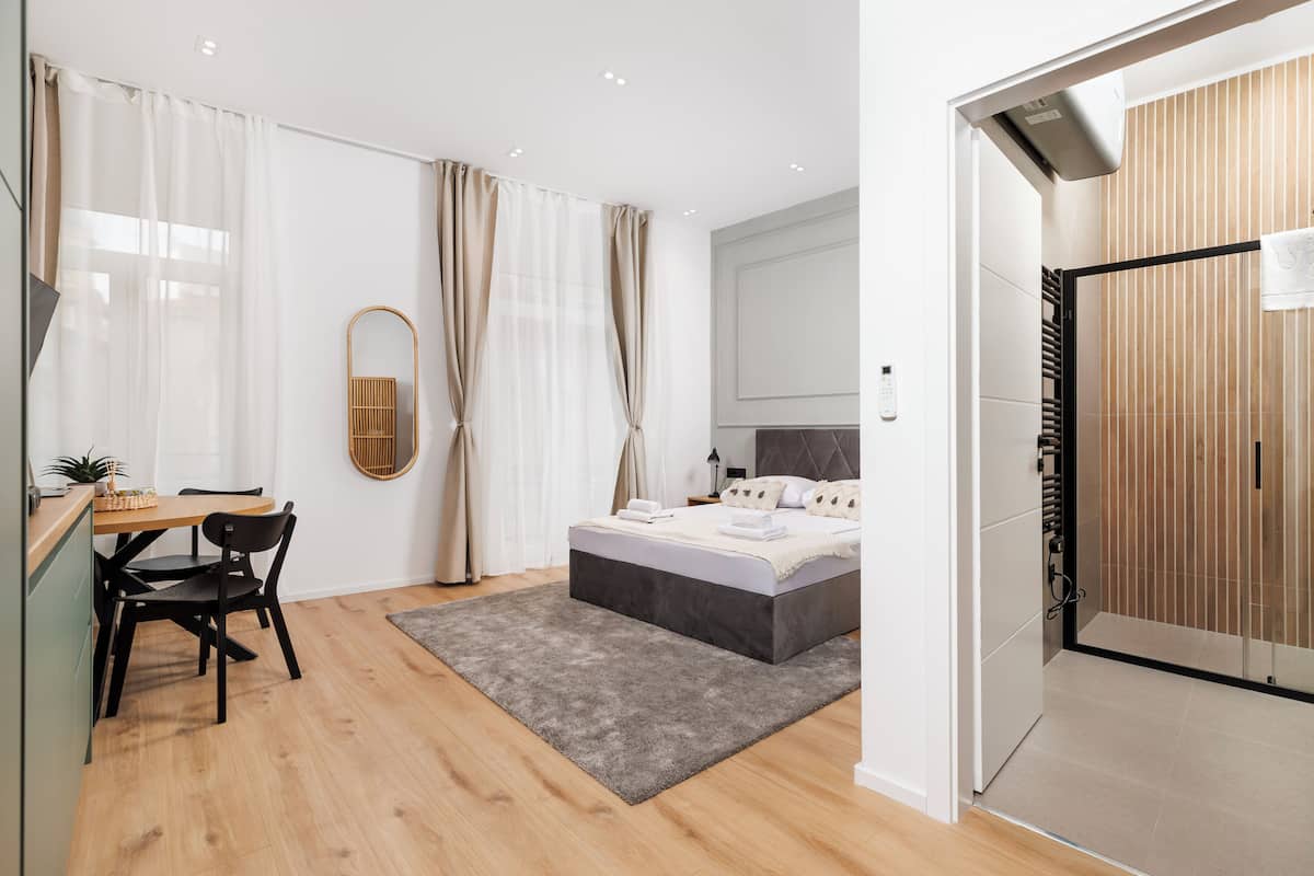 A modern bedroom with a bed, bedside table, and a desk with a chair.