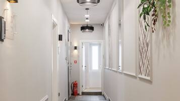 A hallway with patterned flooring, wall-mounted lights, and a fire extinguisher.