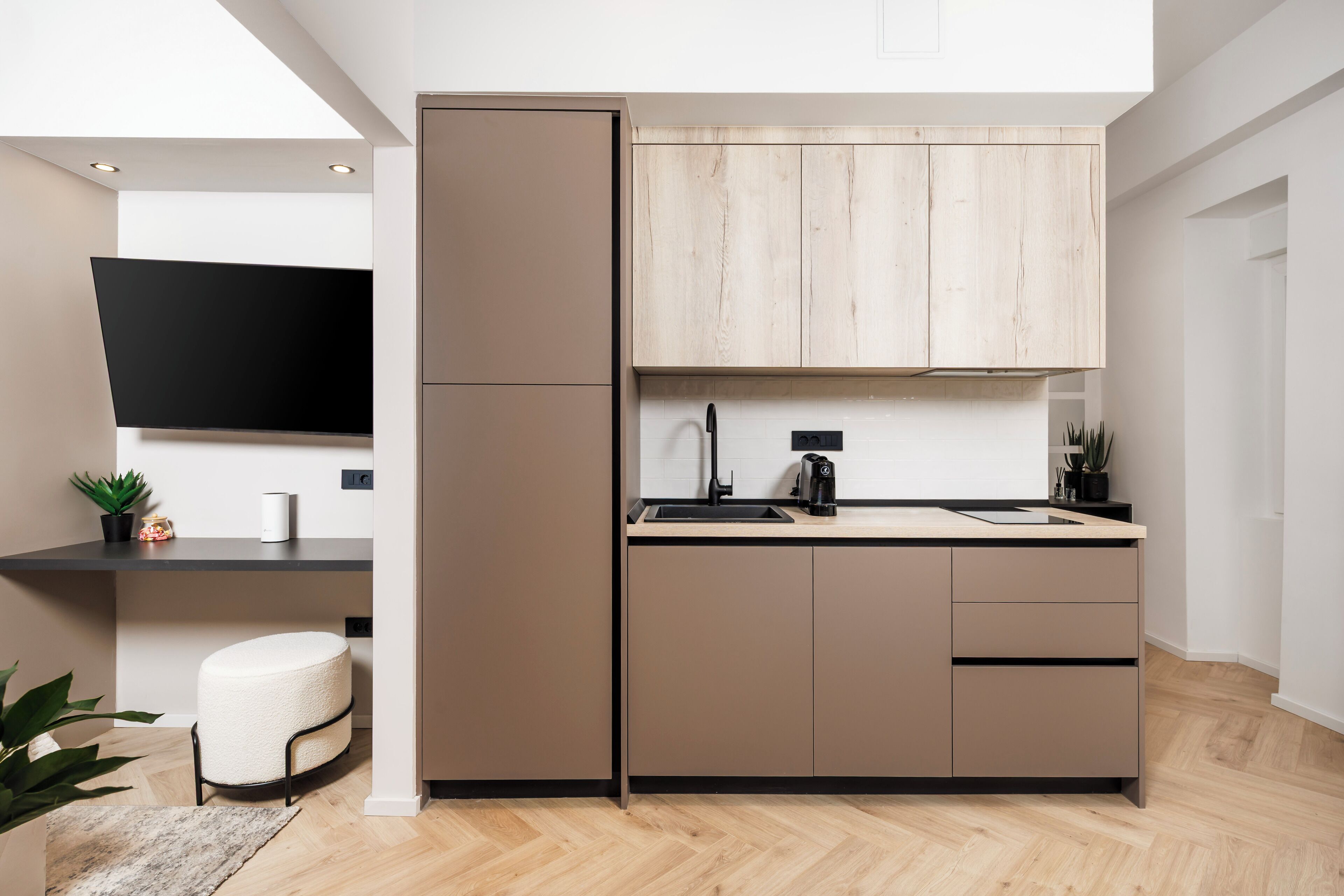 A modern kitchen with a built-in oven, a sink, and a wooden cabinet above the countertop.