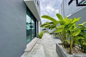 A narrow outdoor corridor with potted plants and a glass wall reflecting the sky. - Villa 19 Private Pool Langkawi (Langkawi)