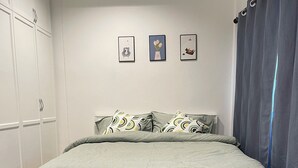 A bedroom with a bed, a wardrobe, and three framed pictures on the wall. - Lovely 3-bedroom house with AC in Minburi (Krung Thep Maha Nakhon)