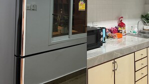A modern kitchen with a stainless steel refrigerator, wooden cabinets, a microwave, and a sink. - Lovely 3-bedroom house with AC in Minburi (Krung Thep Maha Nakhon)