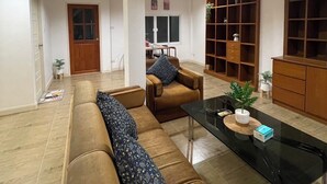 A spacious living area with a sofa set, a coffee table, and a bookshelf. - Lovely 3-bedroom house with AC in Minburi (Krung Thep Maha Nakhon)