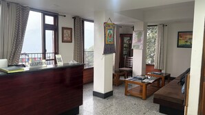 Zona de recepción con un mostrador, sillas, un sofá y vistas al exterior.