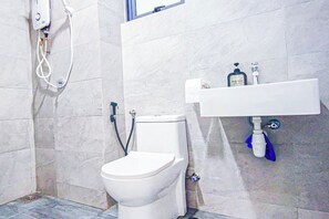 Une salle de bain avec des toilettes, un lavabo et une douche.