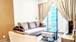 A modern living room with a sofa, a glass coffee table, and a TV stand. - Mall Suite at Sunsuria Setia Alam by HCK (Petaling)