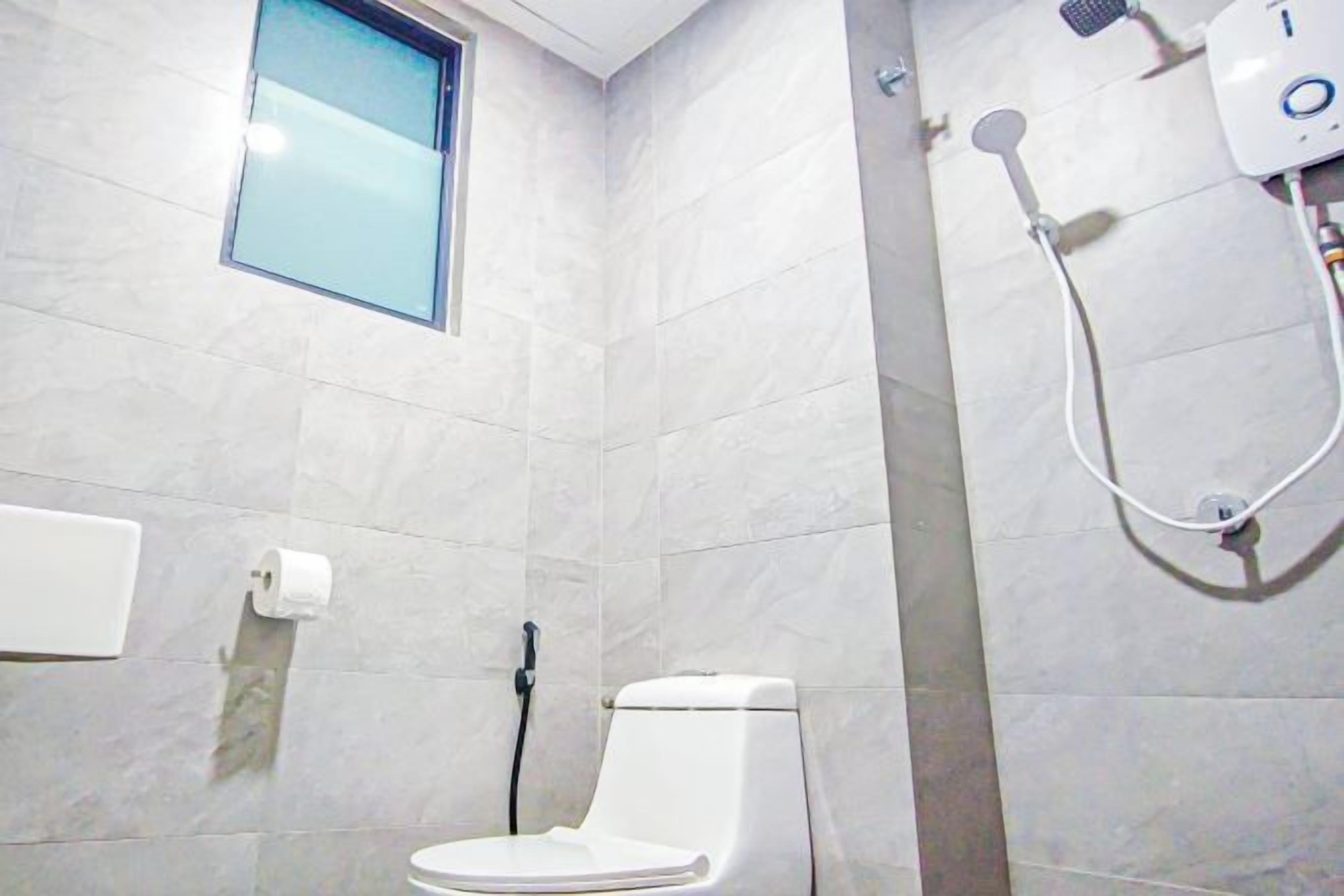 A bathroom with a toilet, a shower, and a window.