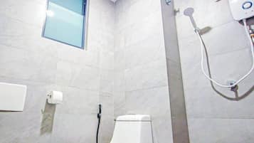 A bathroom with a toilet, a shower, and a window.