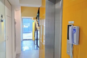 A hotel corridor with a reception area, a phone, and a door leading to the outside. - Look Home Guesthouse in Myeong-dong (Seoul)